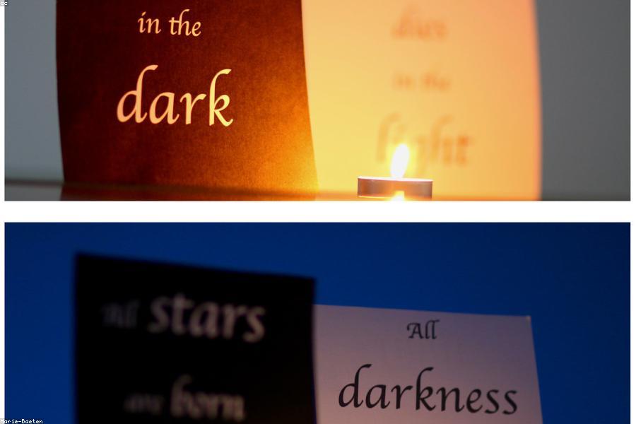 A candle burning on a windowsill beside an open notebook