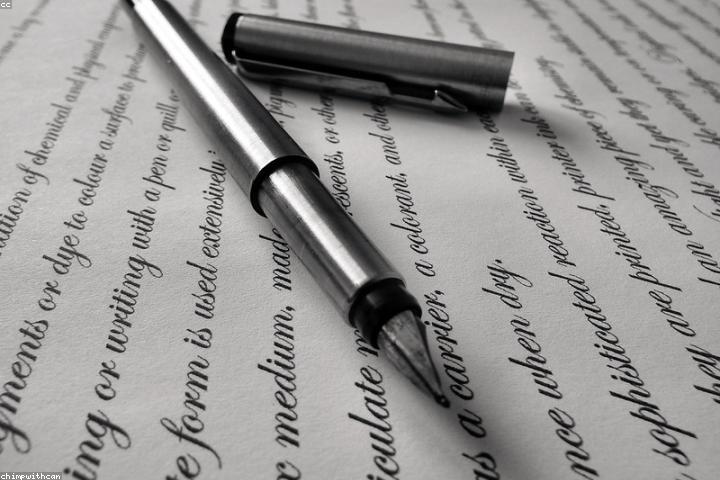 Fountain pen resting on cream paper covered in handwritten script